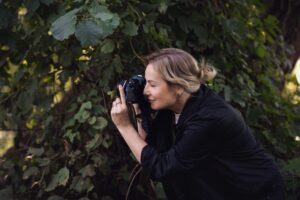 Na jasnym, ręcznie czerpanym arkuszu papieru widnieje krótki napis zapisany stylizowanymi literami alfabetu hebrajskiego. Niektóre znaki przypominają gałązki drzew, a obok jednego z wyrazów znajduje się niewielki czarny motyw kwiatu. Papier ma nieregularne, postrzępione krawędzie i został umieszczony na białym tle.